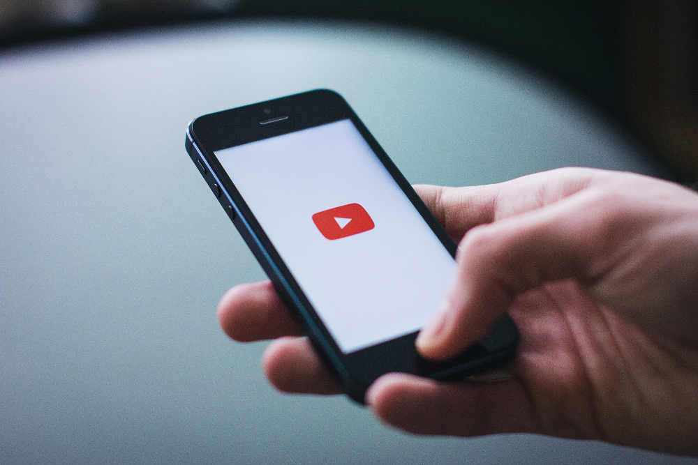 Das Foto illustriert die mobile Nutzung von Videoportalen wie Youtube: Es zeigt eine Detailaufnahme eines Handys, auf dem Display das Logo von Youtube.